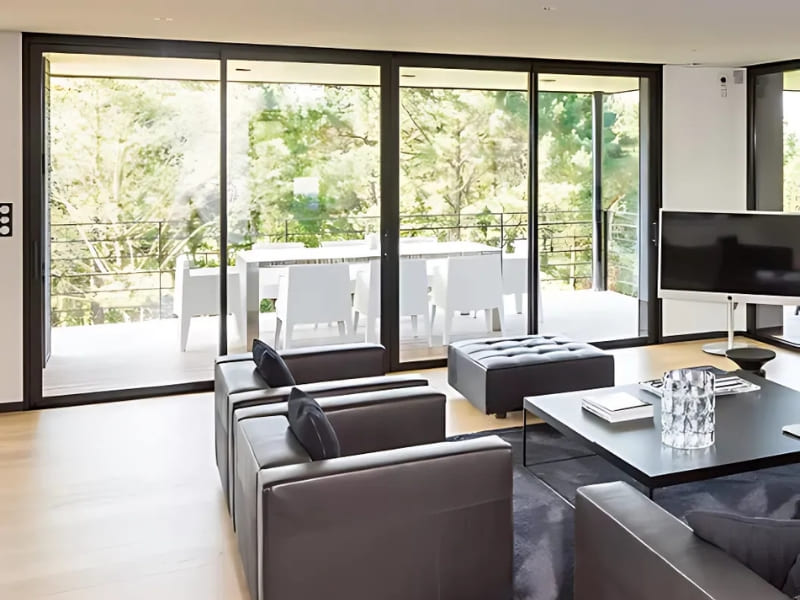 Photo intérieure d'un salon avec de grandes baies vitrées en aluminium de couleur noire.