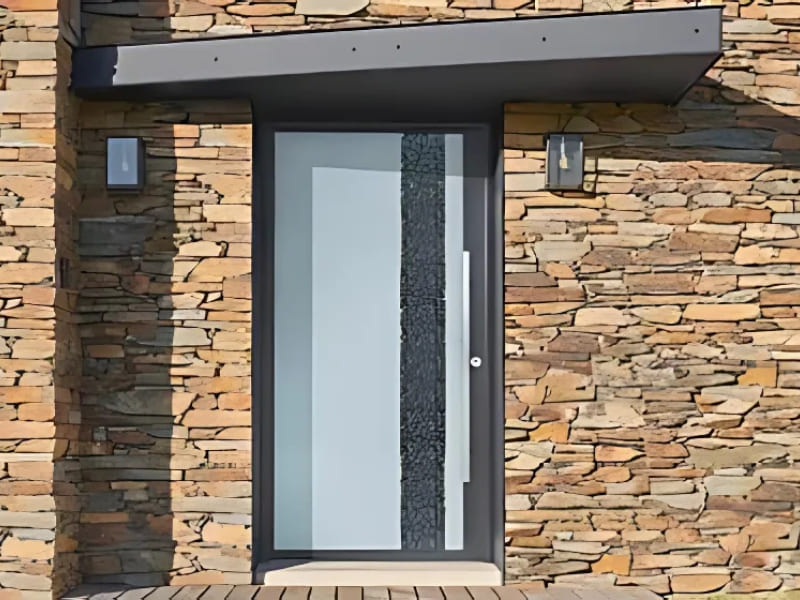 Photo extérieure d'une maison avec une porte d'entrée en aluminium de bicolore gris clair et gris foncé.