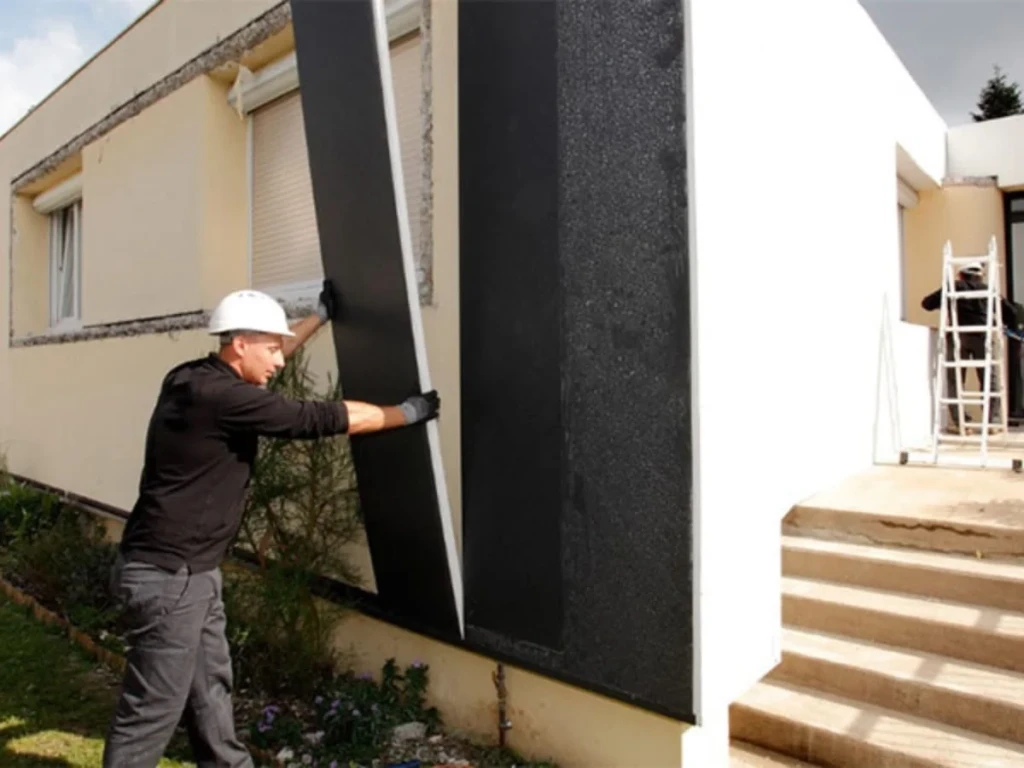 Technicien procédant à l'installation de panneaux de revêtement Uniso pour l'isolation extérieur d'une maison.